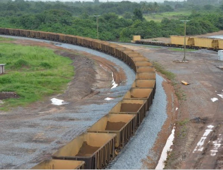 A train loaded with iron ore winds through a rail yard, highlighting the vital role of the mining sector in the Liberia's economy and export trade